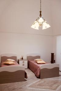 ein Schlafzimmer mit zwei Betten und einem Kronleuchter in der Unterkunft Villa Rosanna's Haven-Relax a pochi minuti da Monopoli in Antonelli
