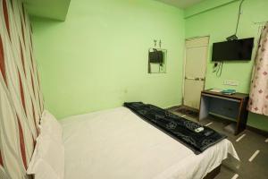 a small room with a bed and a television at Rai Guest House in Ujjain