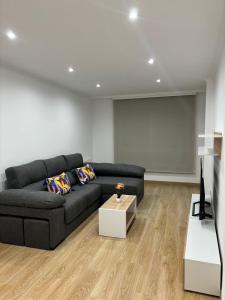 a living room with a black couch and a screen at Alesamar A in Burela de Cabo