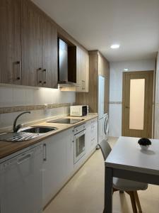 a kitchen with white appliances and a table in it at Alesamar A in Burela de Cabo