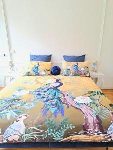 a bed with a blanket with peacocks on it at L'Instant Rémois - Hypercentre Boulingrin in Reims