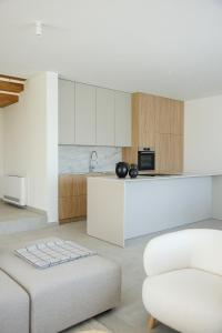 a kitchen with white cabinets and a white couch at Villa Olea - villa with heated pool, sauna and gym in Kaštela