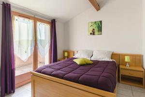1 dormitorio con cama morada y ventana en Lagrange Vacances Les Maisonnettes, en Sainte-Marie-Plage