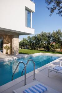 a swimming pool with two lounge chairs in front of a house at Villa Olea - villa with heated pool, sauna and gym in Kaštela