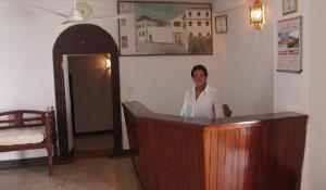 a woman is standing behind a wooden podium at Riverman Hotel in Zanzibar City