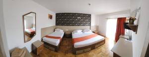 a hotel room with two beds and a mirror at Complex Ramiro in Suceava