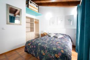 a bedroom with a bed with a floral blanket at Casa Rural La Rosalia in Cogolludo