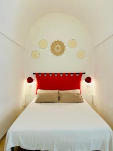 a bedroom with a white bed with a red headboard at Casa Cassiopea Céglie Messapica in Ceglie Messapica