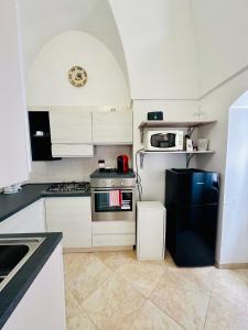 a kitchen with white cabinets and a black refrigerator at Casa Cassiopea Céglie Messapica in Ceglie Messapica