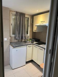 a small kitchen with white cabinets and a sink at Appart Hôtel Paris La Défense in Colombes