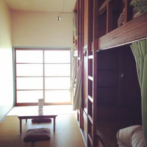 une chambre avec un lit et une table devant une fenêtre dans l'établissement Amanohashidate Youth Hostel, à Miyazu