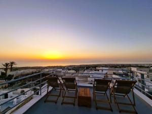 a balcony with three chairs and a sunset at Kykladonisia Traditional Settlement in Fira +89 photos