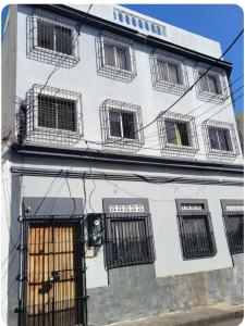a white building with barred windows and a door at Amplio apartmento in Santo Domingo