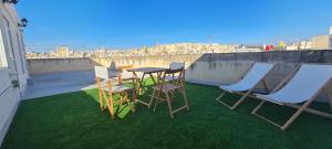 d'une table et de chaises sur un balcon avec de l'herbe verte dans l'établissement Casa Marie, Stay in a Traditional Corner Townhouse in the 3 cities, built in 1881, à Cospicua