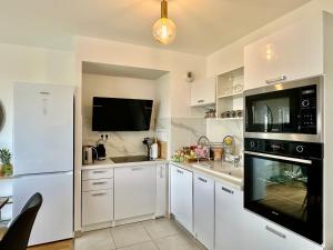 a kitchen with white cabinets and a black appliance at Appt Vue Parc Disneyland-PARIS - Terrasse - Parking Privé in Chessy