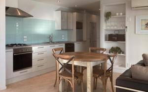 una cucina con tavolo e sedie in legno in una stanza di Seascapes Waterfront 2 a Paraparaumu