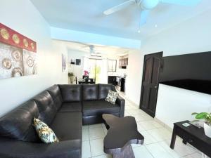 a living room with a leather couch and a table at Charming Condo Orchidea in Coco