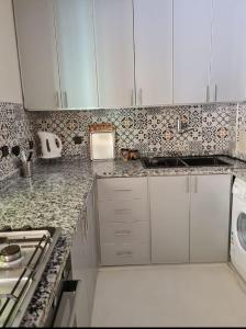een keuken met marmeren aanrechtbladen en witte kasten bij Mestura Marina Tanger in Tanger +12 foto's