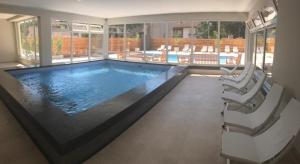 une grande piscine dans une maison avec deux chaises dans l'établissement Del Sol Dto 210, à Pinamar