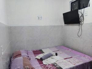 a bed in a room with a tv on the wall at Pousada Terra do Sol in Fortaleza