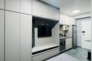 a white kitchen with white cabinets and a tv at Zyz Centro in Sao Paulo