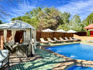 a swimming pool with chairs and a gazebo at Lodge Ancar Atacama in San Pedro de Atacama