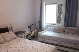 a bedroom with two beds and a bike in it at Maresias Cond Club Alto padrão Frente Praia in São Sebastião +28 photos