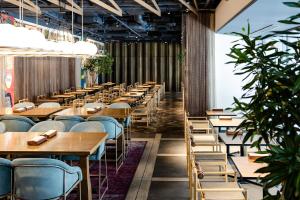 a row of tables and chairs in a room with plants at Cross Hotel Kyoto in Kyoto