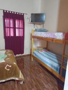 Zimmer mit 2 Etagenbetten und einem TV in der Unterkunft Hostel el Amanecer in Puerto Iguazú