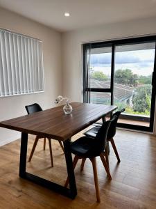 Una mesa de comedor con sillas y una gran ventana. en Cozy Top-Floor Stay with Private Bathrooms & Free Parking, en Auckland 1 foto más