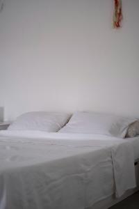 a white bed with white sheets and pillows at Kyon Beach Suites Kythnos in Kanala