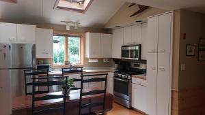 Una cocina con gabinetes blancos y electrodomésticos negros. en Quiet Beach Home, walk to beach access, en Plymouth