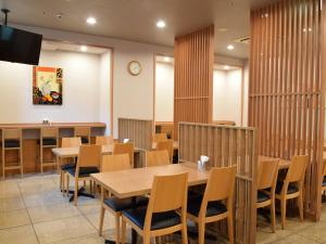 una sala da pranzo con tavoli e sedie in legno di Hotel Route-Inn Kanazawa Ekimae a Kanazawa