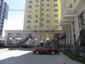 czerwony samochód zaparkowany przed dużym budynkiem w obiekcie Apartment Kievskaya 114/2 w mieście Biszkek