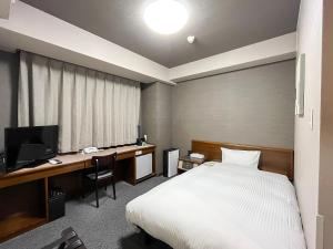 1 dormitorio con 1 cama y escritorio con ordenador en Hotel Route-Inn Daini Nagano, en Nagano