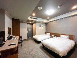 a hotel room with two beds and a desk at Hotel Route-Inn Dai2 Nagano Naganobekkan in Nagano +21 photos