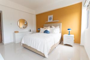 a bedroom with a large white bed and a yellow wall at LANDA MAR BOCA CHICA in Boca Chica