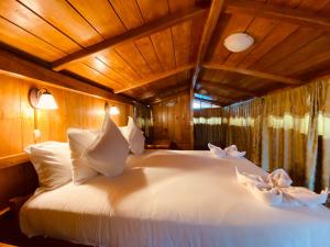 a bedroom with a white bed with a wooden ceiling at Guayabo Hostal Mindo in Mindo