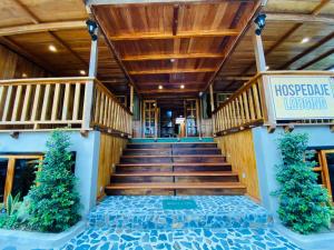 a lobby of a hotel with wooden stairs and a sign at Guayabo Hostal Mindo in Mindo
