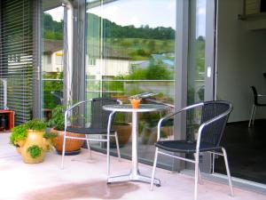 einen Tisch und Stühle auf einem Balkon mit Fenster in der Unterkunft Artist's Loft zur Maloya in Ormalingen