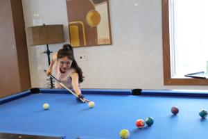 a young girl playing pool with a cue at Discovery Lodge Phong Nha in Cừ Lạc