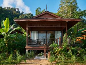 uma pequena casa com uma varanda numa floresta em The Boathouse Pulau Tioman em Ilha Tioman