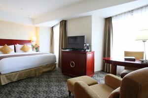 Cette chambre comprend un grand lit et une télévision. dans l'établissement International Resort Hotel Yurakujo, à Narita
