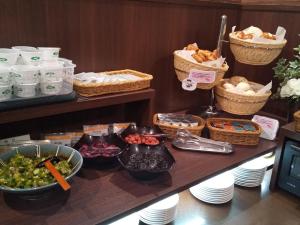 a buffet with bowls of food and baskets of food at Hotel Route-Inn Uozu in Uozu