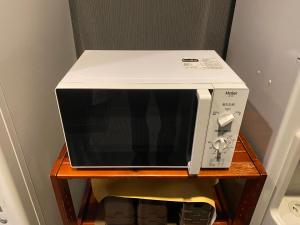 a white microwave sitting on a wooden table at Hotel Route-Inn Uozu in Uozu