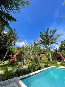 a pool in front of a resort with palm trees at Apit Lawang Villas & Resto in Nusa Penida