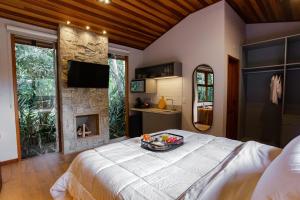 a bedroom with a large bed and a fireplace at Chalé Raizes do Vale in Visconde De Maua