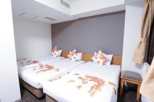 two beds in a room with white walls at Hotel Naha City -Kokusai Street- in Naha