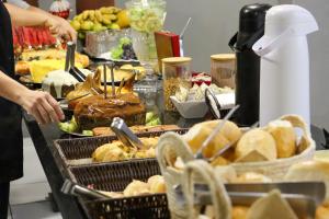 a buffet of food with bread and other foods at Hotel Renata Tubarão in Tubarão