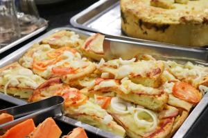 a pizza with tomatoes and onions in a pan at Hotel Renata Tubarão in Tubarão